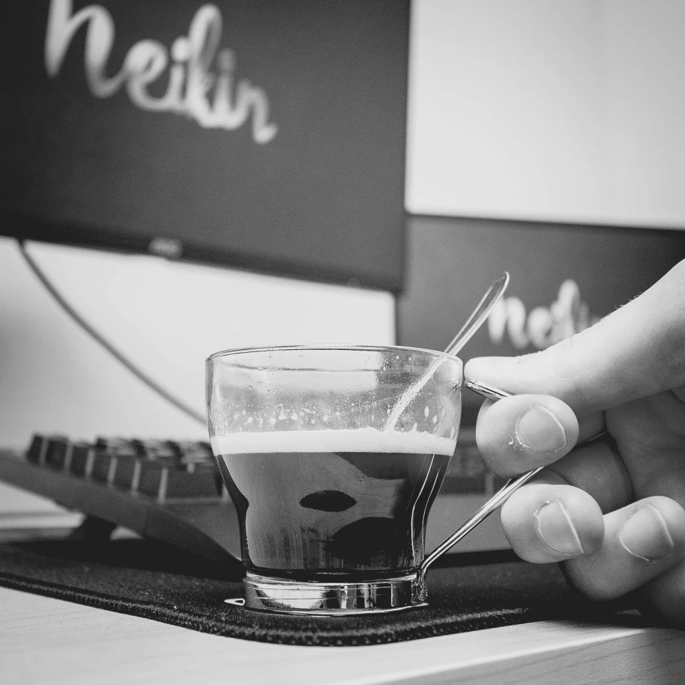 Tasse de café sur un bureau avec en arrière-plan des écrans d'ordinateur dans les locaux de Neikin